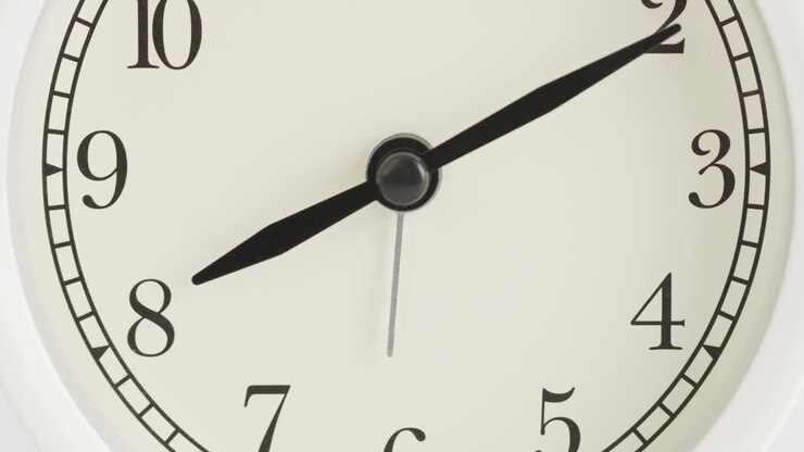 White wall clock tells the time at 8 o'clock.