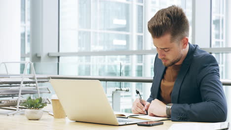 un apuesto joven empresario trabajando en su computadora portátil