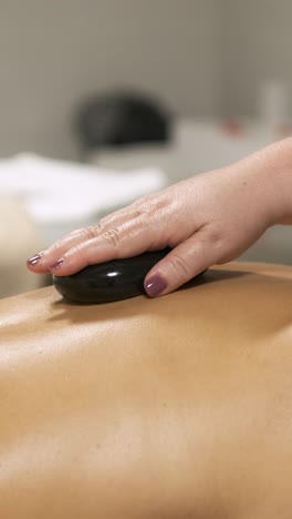 masseuse delivering a relaxing hot stone massage in a tranquil spa setting. vertical