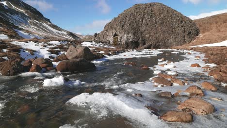 Klarer-Fluss,-Der-Im-Frühjahr-über-Eisbedeckte-Felsen-Fließt