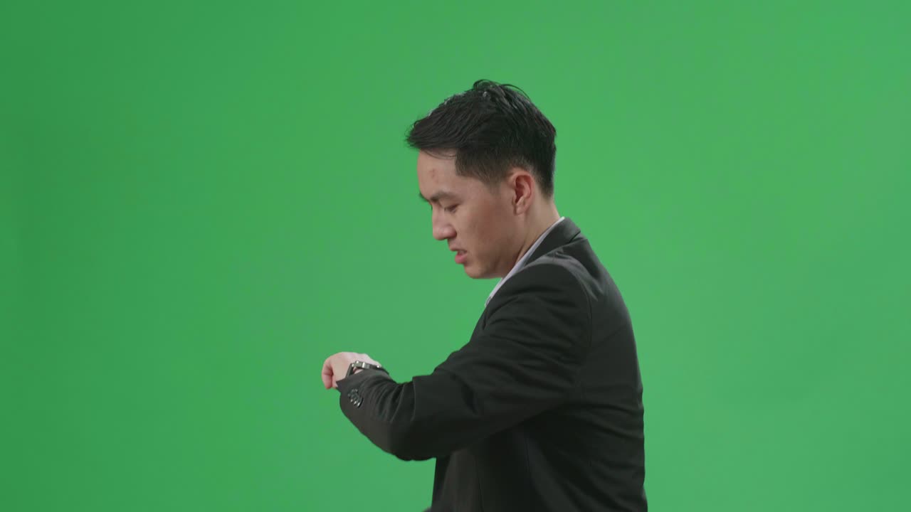 Side View Of Asian Business Man Walking While Looking At Watch And Run On Green Screen Chroma Key