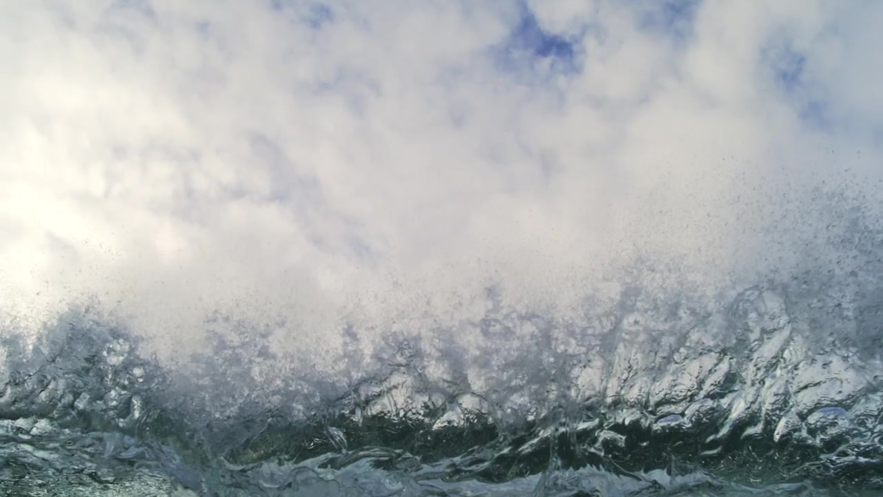 Rounded green ocean swell rolls below overcast clouds near water level in gentle slow motion