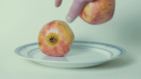 Grabbing-pomegranate-from-plate-against-white-background