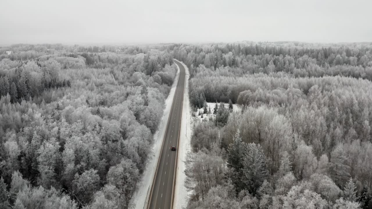 Aerial view of cars driving on a highway in winter landscape. Frozen trees. Hoar and rime on tree in cold winter weather.