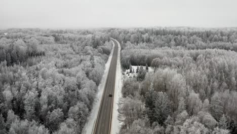 aerial view of cars driving on a highway in winter landscape. frozen trees. hoar and rime on tree in cold winter weather.