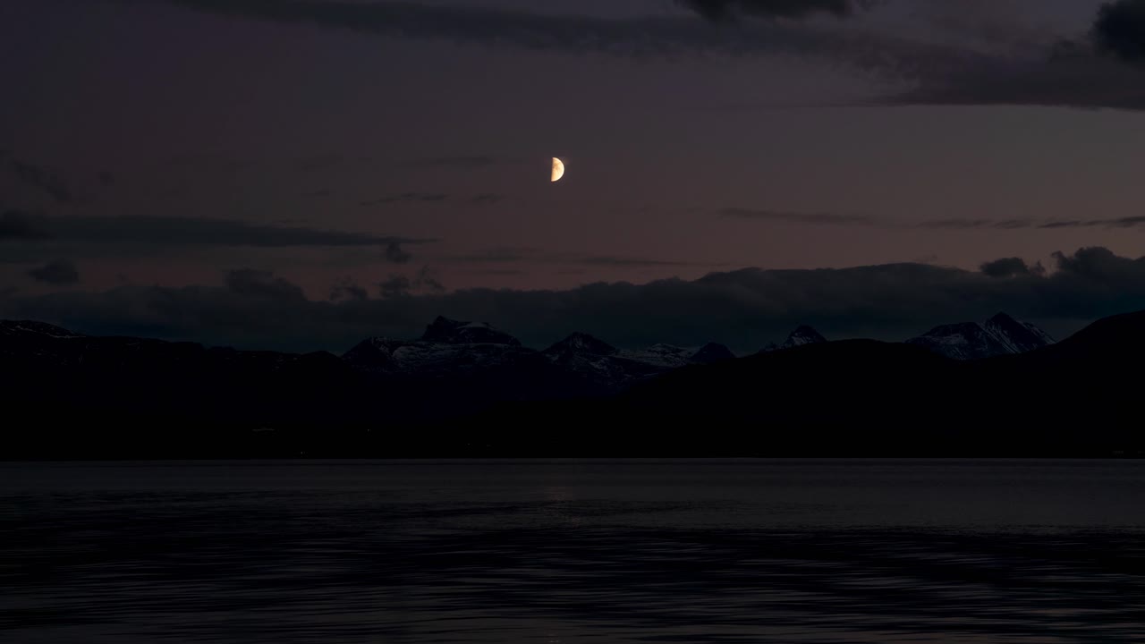 Selang waktu yang indah dari bulan yang mengawasi pemandangan laut dan gunung
