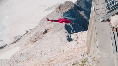 red cargo helicopter operates on the zugspitze highest mountain in germany