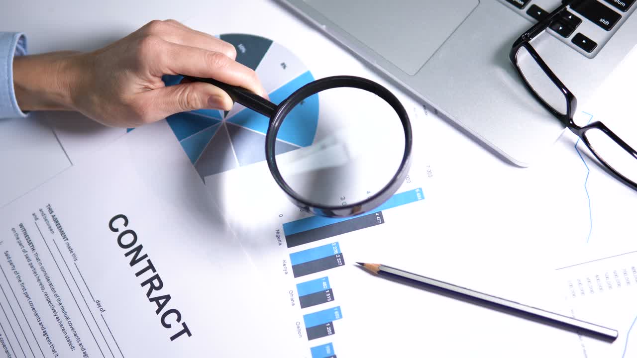 persona que estudia gráficos usando lupa antes de rellenar el contrato, análisis
