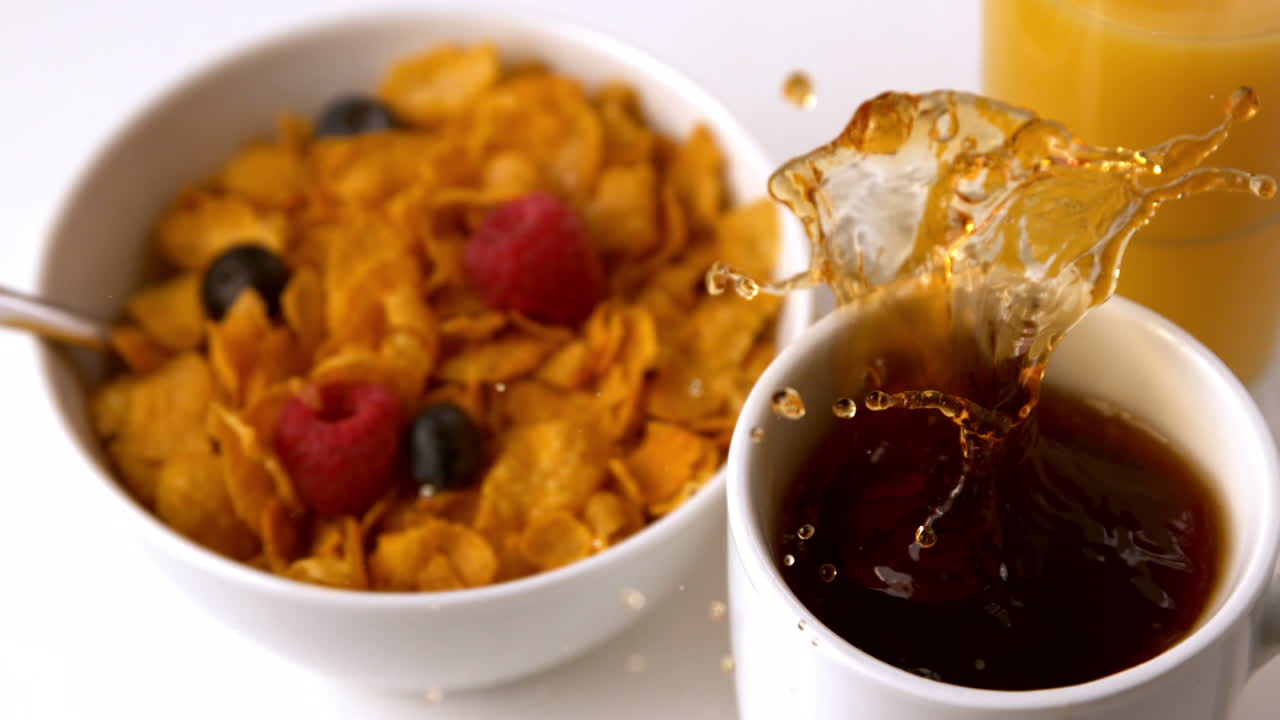 un cubo de azúcar cayendo en una taza en la mesa del desayuno