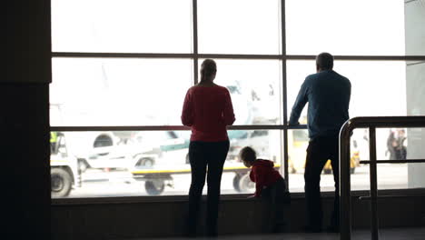 una joven familia observando aviones en un aeropuerto
