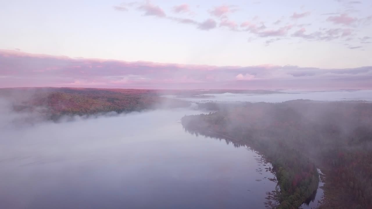 캐나다 온타리오 카와타스의 안개 낀 호수와 분홍 구름, 가을 숲 색깔을 드러내기 위해 구름 안개를 뚫고 날아가는 공중 일출 와이드 샷