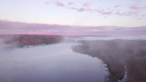 Weitwinkelaufnahme-Des-Sonnenaufgangs-Aus-Der-Luft,-Der-Durch-Wolkennebel-Fliegt,-Um-Neblige-Seen-Und-Rosafarbene-Wolken-Und-Herbstwaldfarben-In-Kawarthas,-Ontario,-Kanada,-Zu-Enthüllen