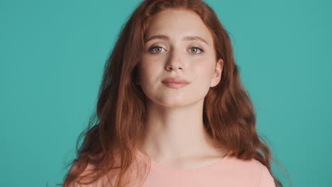 Redheaded-girl-in-front-of-camera-on-turquoise-background.