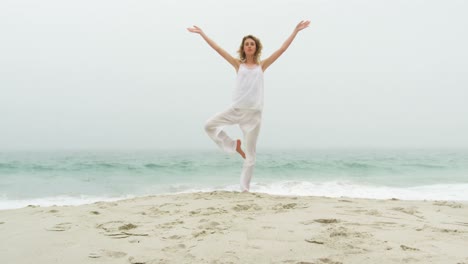 Vista-Frontal-De-Una-Mujer-Caucásica-Realizando-Yoga-En-La-Playa-4k