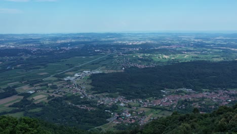 drone panorama of the ivrea morainic amphitheatre seen from brosso, val chiusella, italy, showing lush green plains, woods, and scattered villages under clear sky, high drone shot, slow motion