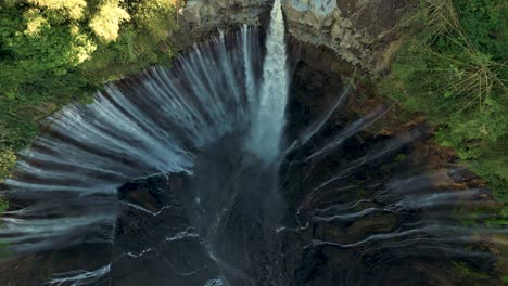 bird eye view looking down to tumpak sewu waterfall and its hundred waterfalls in a sunny morning - east java, indonesia