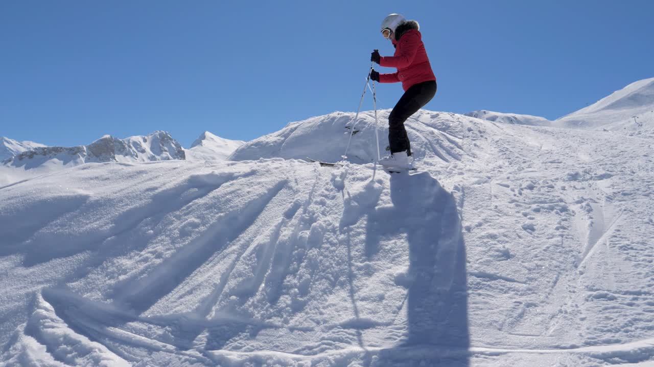 элегантный лыжник спускается на лыжах к краю лыжного склона и восхищается панорамой