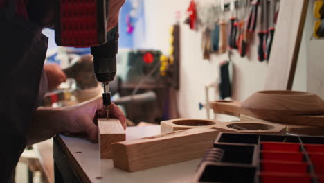 carpenter sinks screws into wooden surfaces with power drill, close up