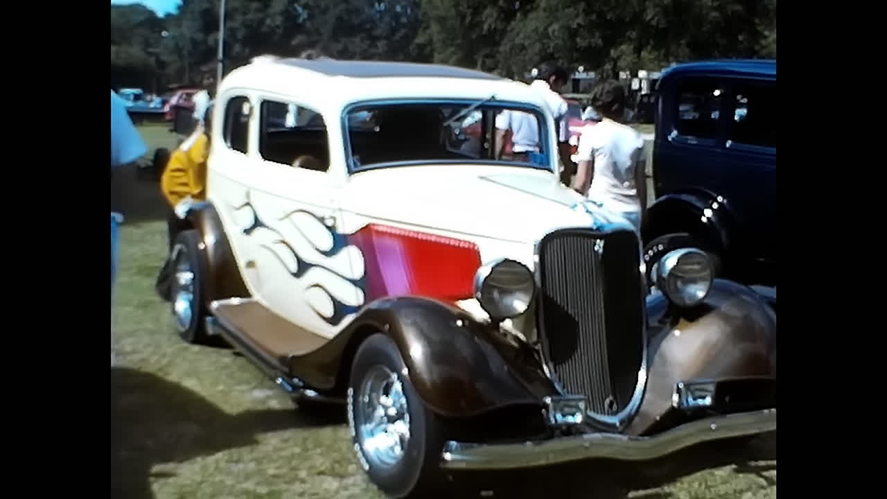 Group of Spectators Surrounding Classic White and Red Car at 1970s American Car Show. CIRCA USA - 1970s: Spectators gather around a vintage white and red car at an American car show in the 1970s.