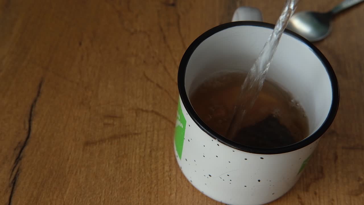 Sugar and hot water added to cup with tea bag to brew hot cup of tea