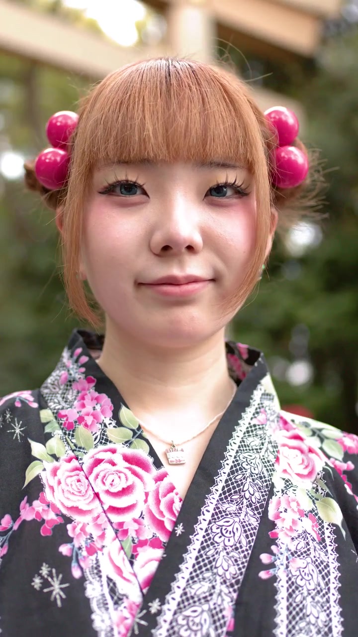 Tokyo'da bir Şinto tapınağının dışında geleneksel çiçekli yukata giymiş genç bir kadın duruyor.
