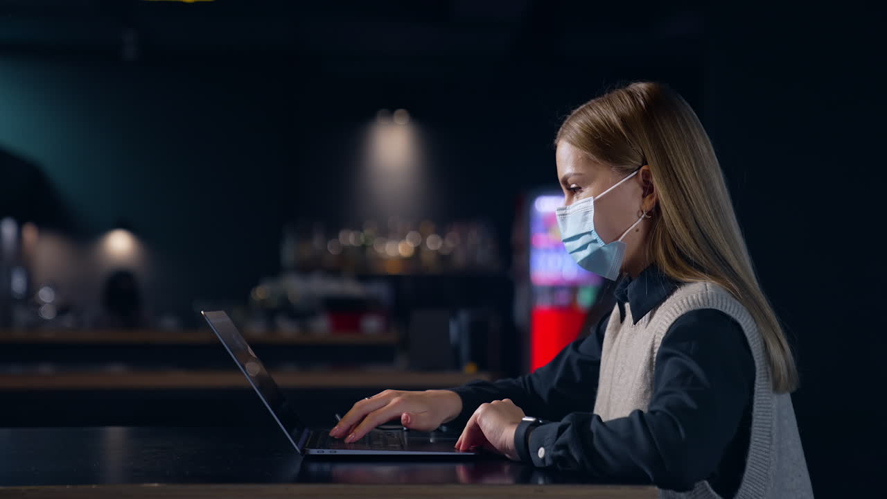 Portrait quarantine employee in mask. Pretty young lady in mask working with computer.