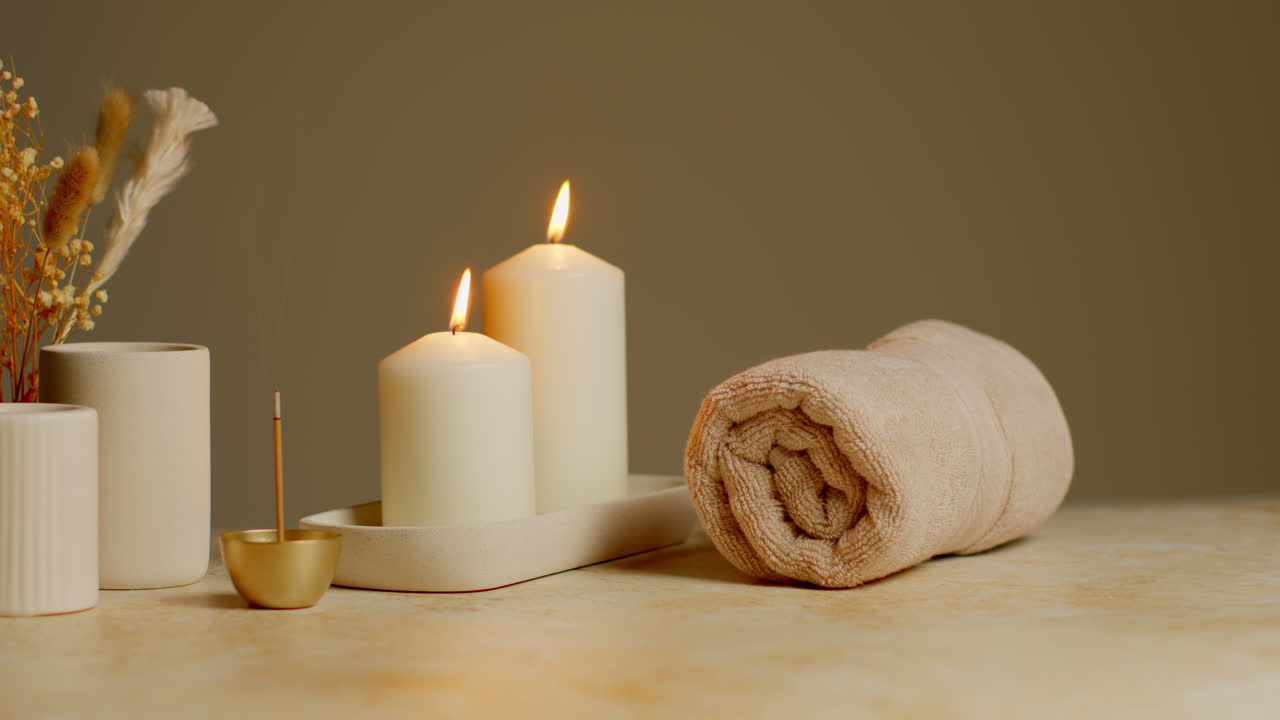 vida muerta de velas encendidas con hierbas secas, incienso y toallas suaves como parte de la relajante decoración del día de spa 1
