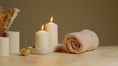 Still-Life-Of-Lit-Candles-With-Dried-Grasses-Incense-Stick-And-Soft-Towels-As-Part-Of-Relaxing-Spa-Day-Decor-1