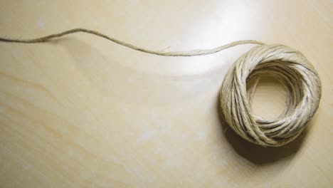 stop motion of a ball of string unrolling untill it end, on a light wooden background