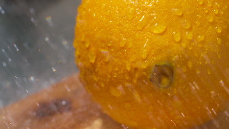 rinsing a freshly picked, whole, ripe orange in the sunlight