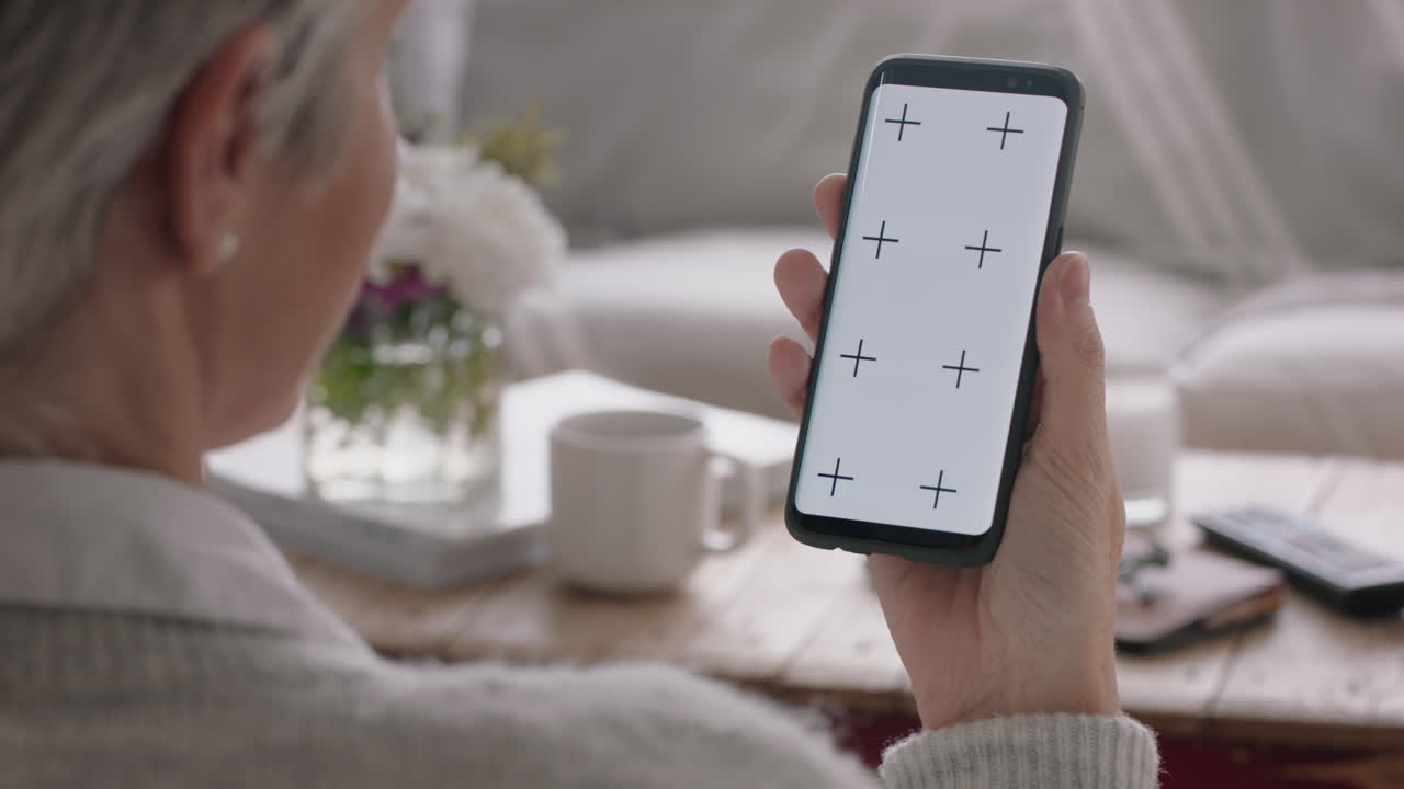 mujer madura teniendo video chat usando smartphone pantalla verde abuela charlando mirando a la llave croma disfrutando de la pantalla compuesta del teléfono móvil en orientación vertical 4k metraje