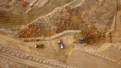 vista aérea de la excavadora de excavación de la cantera de roca y los camiones están cargando rocas