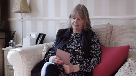 senior woman reading tablet on couch at home
