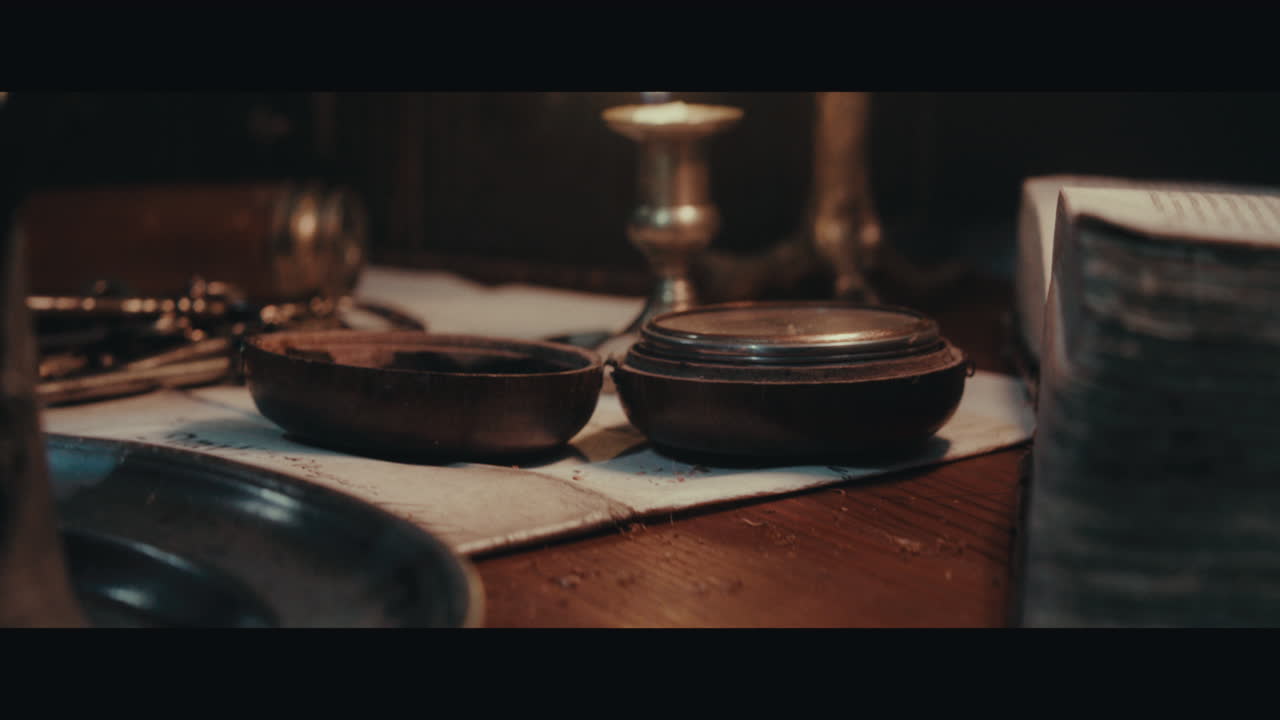 An old compass on the table filled with documents and maps inside the sailing ship cabin