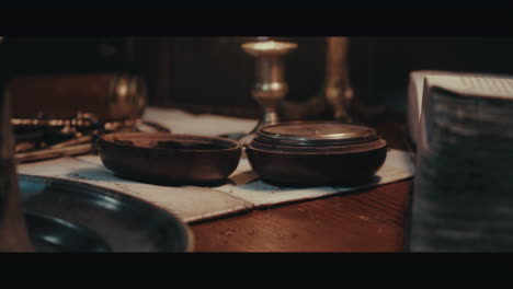 an old compass on the table filled with documents and maps inside the sailing ship cabin