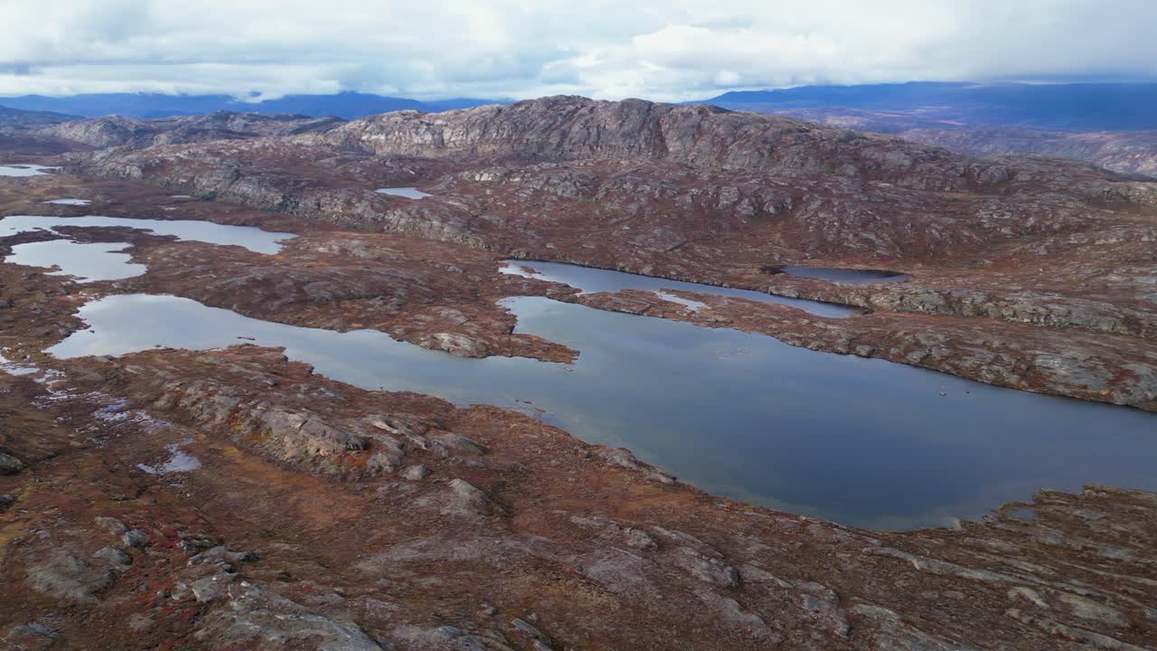 Flyover rocky arctic tundra meltwater lakes in Greenland mountains