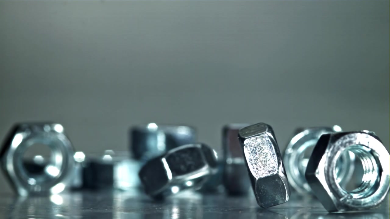 光沢のある金属製六角ナットが落下するスローモーション