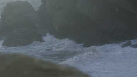 vista desde la cima de la colina de la playa áspera olas del mar rompiendo en cámara lenta con el agua lanzando alto en el aire. imágenes del océano costa durante la tormenta natural condiciones de viento en el reino unido 4k.