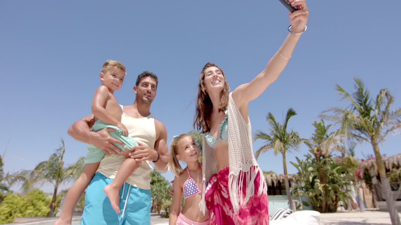 Familia caucásica feliz tomándose una selfie con un smartphone en una casa de playa.