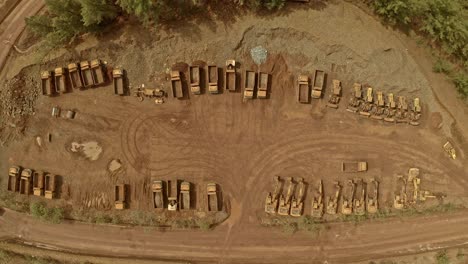 Aerial-Top-Down-View-Over-Parked-Trucks-and-Diggers-on-Muddy-Soil