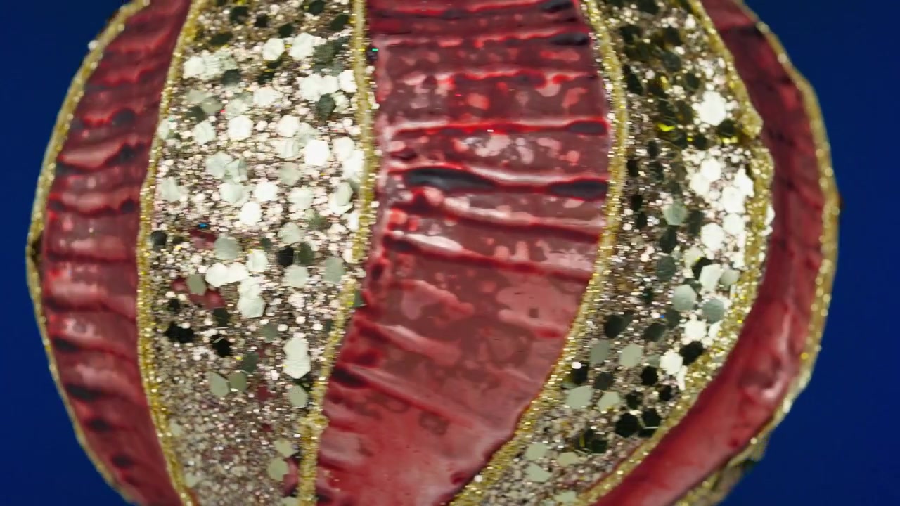 Primo piano di un ornamento natalizio rosso e oro glitterato che ruota