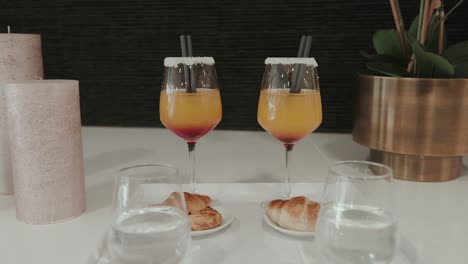 orange and red layered drinks with croissants on elegant table setup