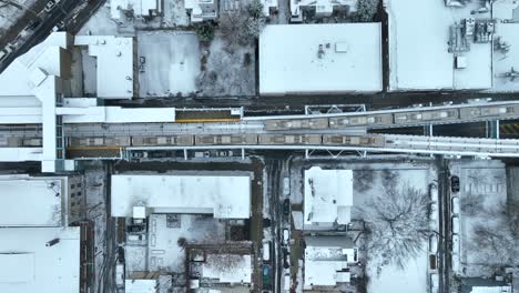 Urban-city-trains-passing-on-elevated-train-tracks-covered-in-snow-during-winter