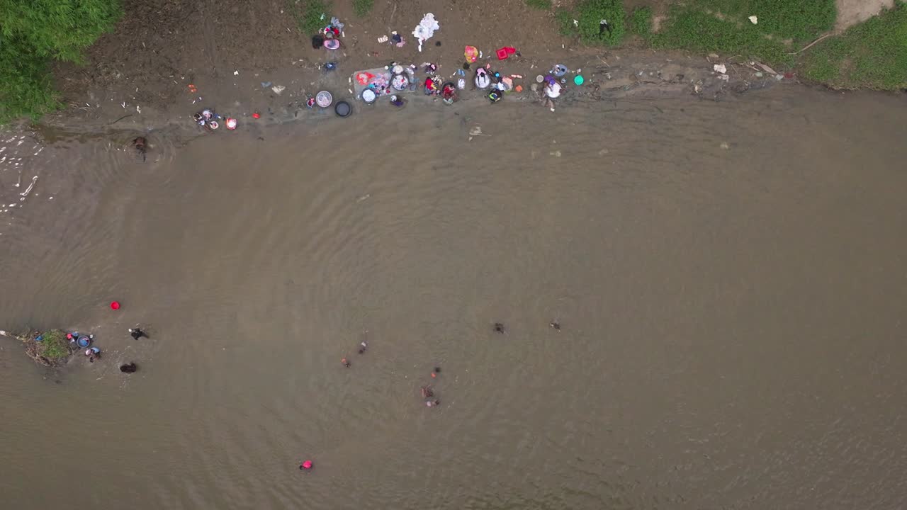 Bovenaanzicht van Haïtiaanse vrouwen die kleding wassen in de Massacre-rivier in Dajabón, Dominicaanse Republiek, aan de grens met Haïti
