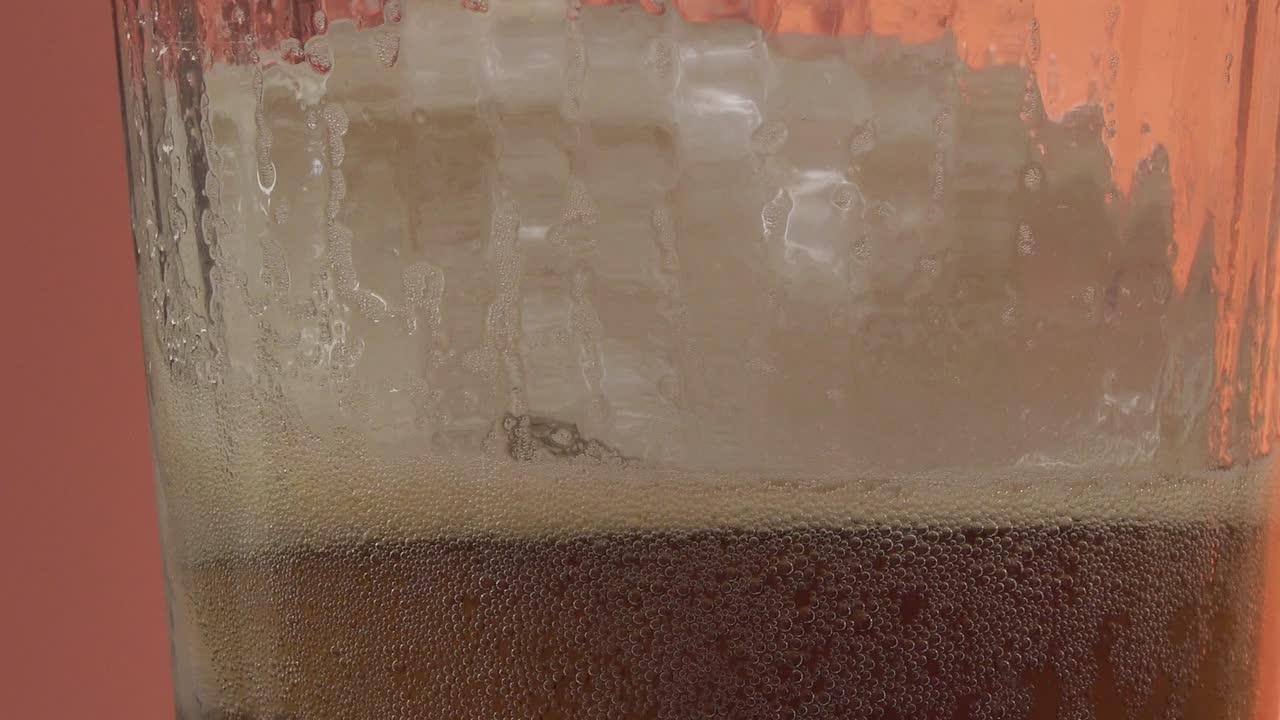Nærbillede af et glas kold, brusende drik med is