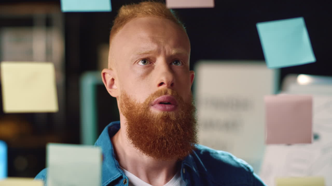 сосредоточенный бизнесмен наклеивает наклейку на прозрачную стену в темном офисе.