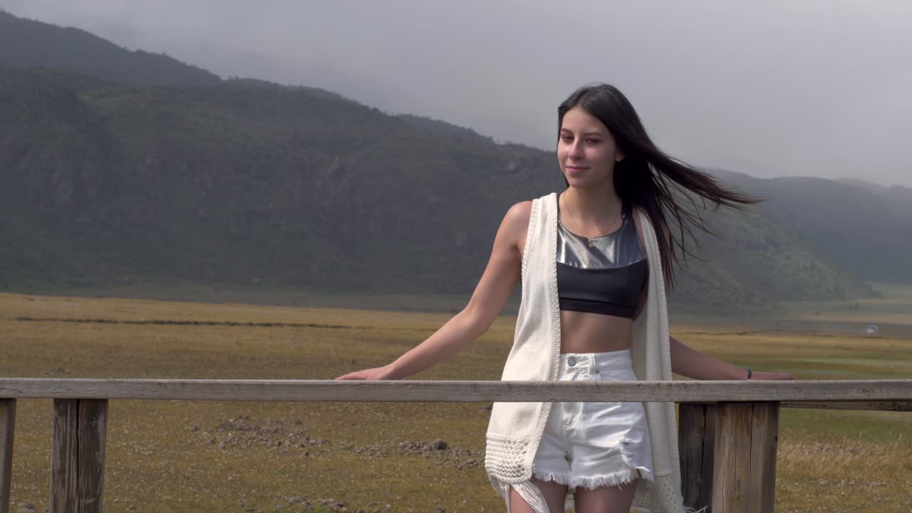 Frontal view of woman gazing into distance, fixing hair as it blows in wind, ecuador