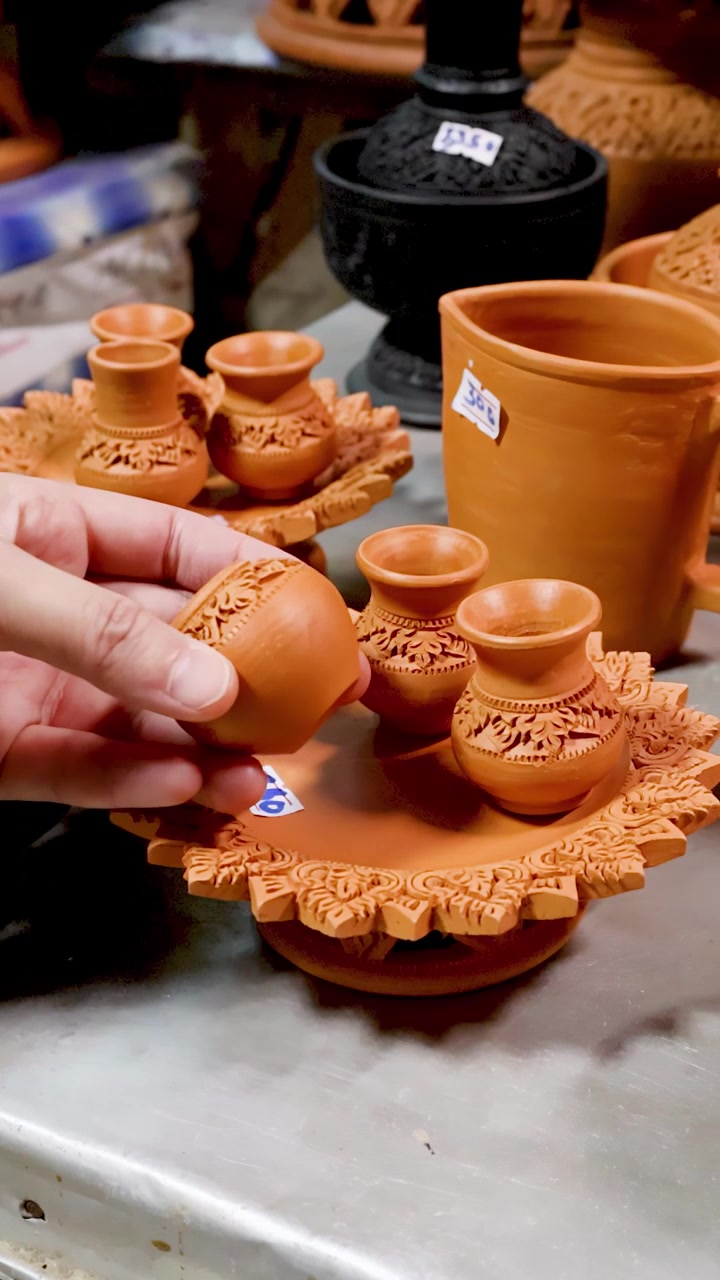 Primer plano de una mano seleccionando cerámica de arcilla hecha a mano en un mercado tradicional de souvenirs.