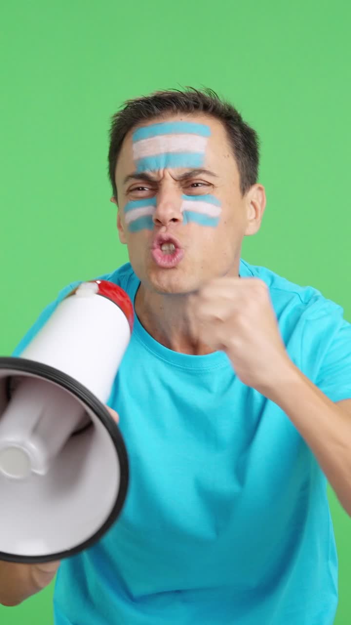 Excited man with argentine flag on face using a megaphone