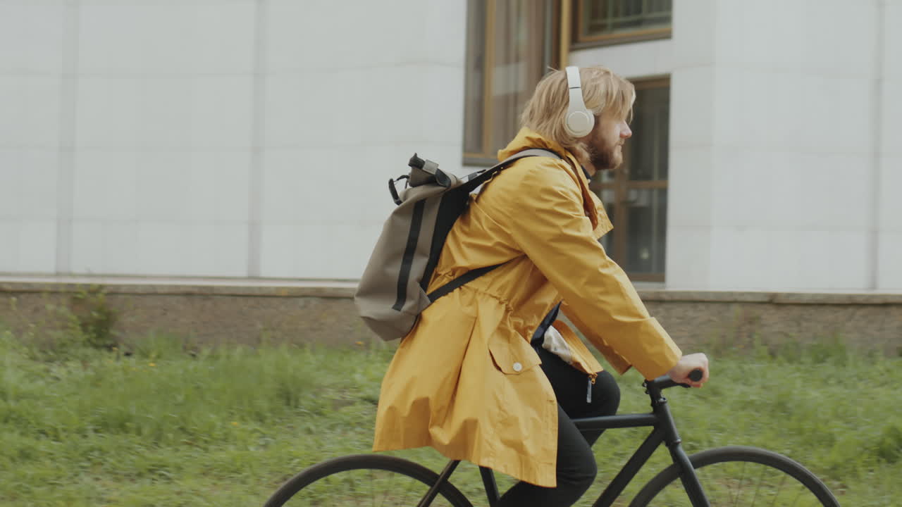 Man in Headphones Cycling on City Street
